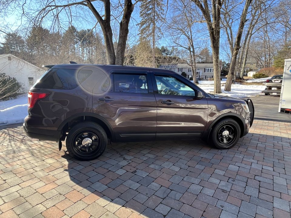 Brown Ford Explorer Police Interceptor Utility, front view with push bar, in paved driveway