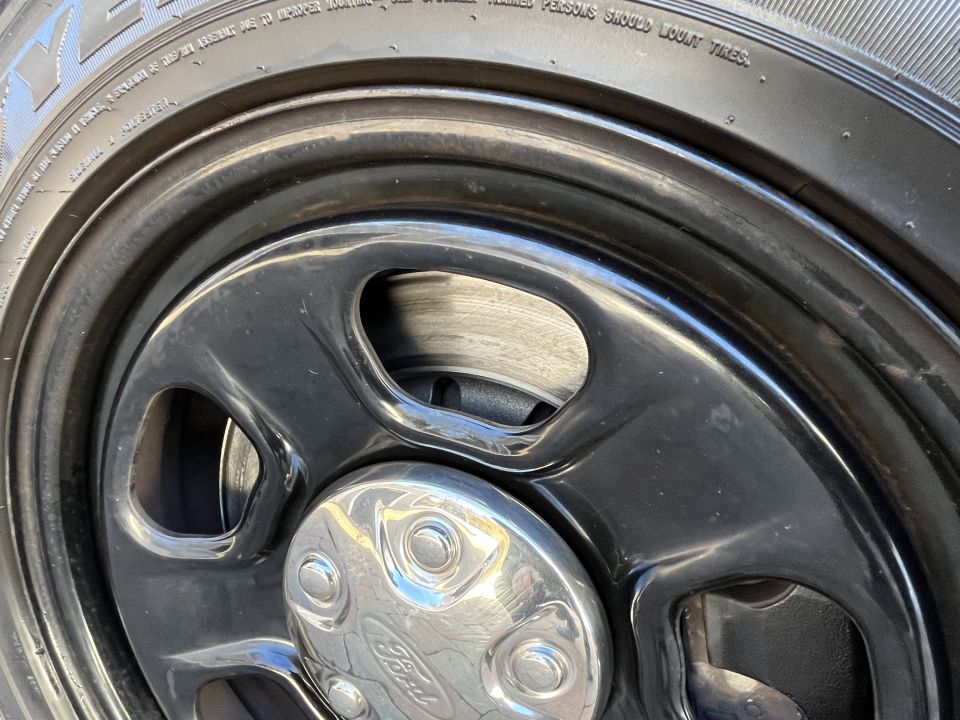 Close-up of black steel wheel with Ford center cap and tire