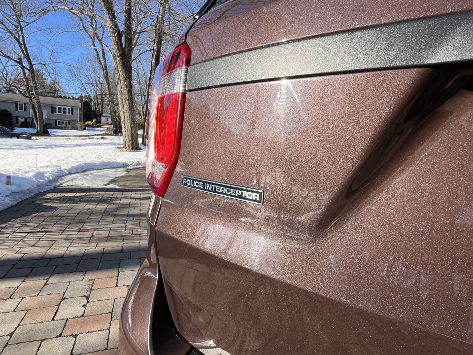 Close-up of brown Ford Police Interceptor rear quarter panel and taillight in a driveway