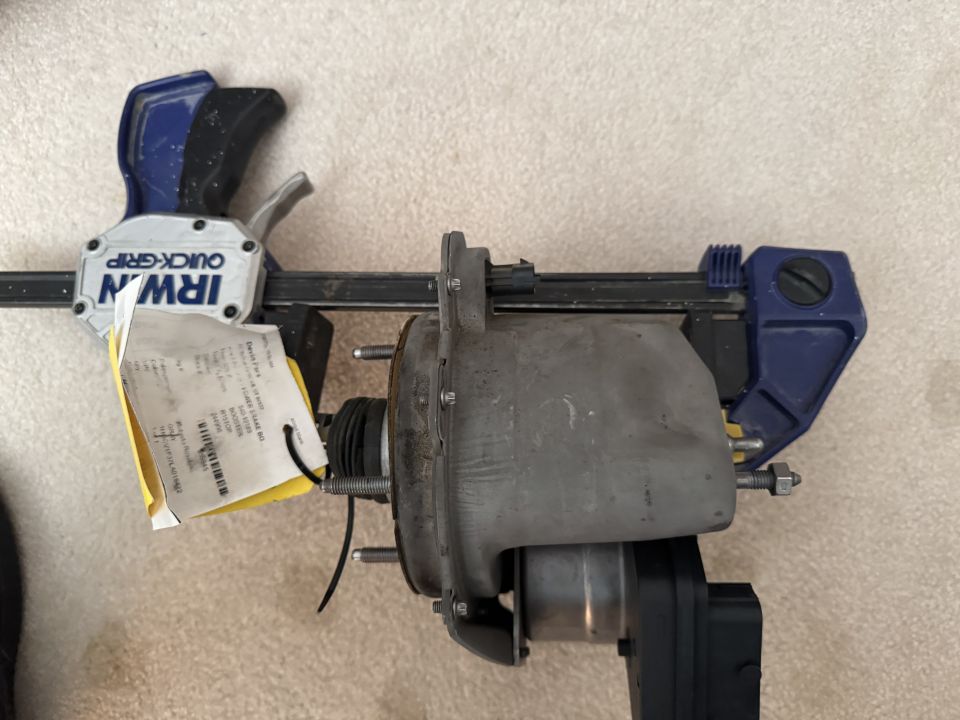 Vehicle brake booster assembly clamped by IRWIN Quick-Grip, with a yellow tag attached.