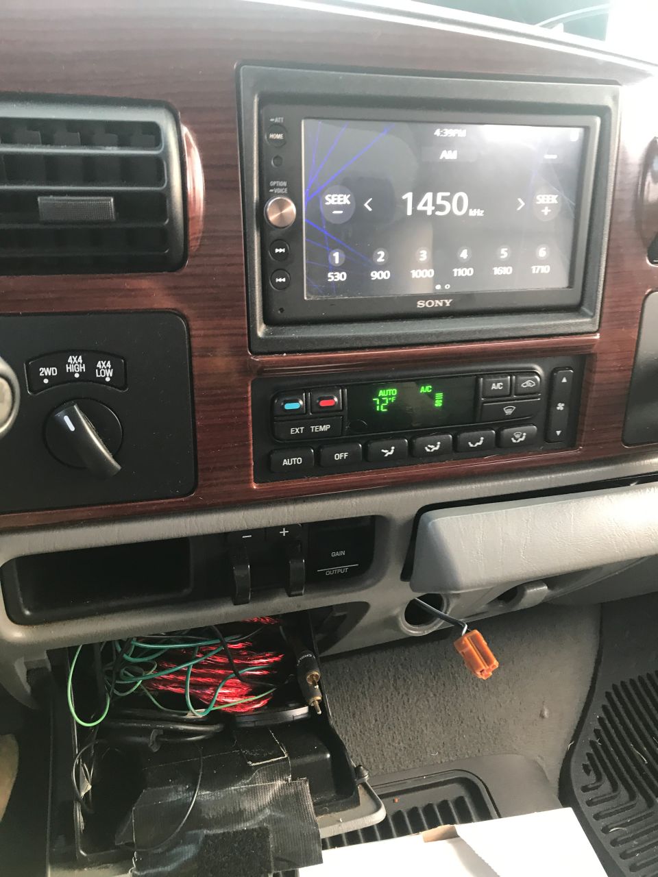 Interior dashboard of a vehicle with a Sony stereo, climate controls, and an open compartment with wires.