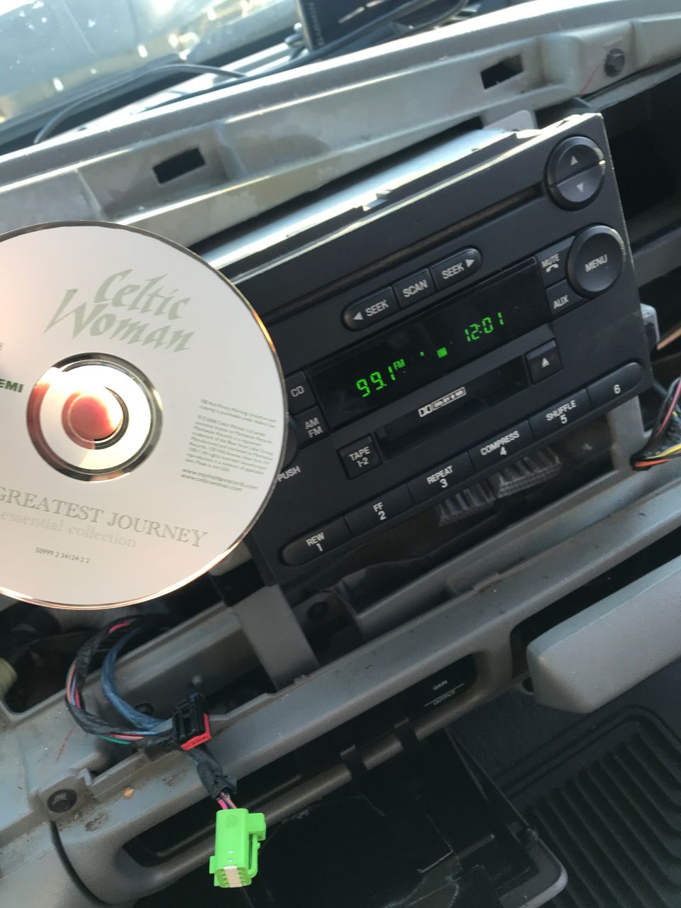 CD by Celtic Woman next to a car stereo with FM radio displayed.