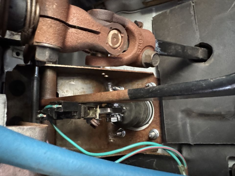 Rusty steering column components with wiring and black housing.