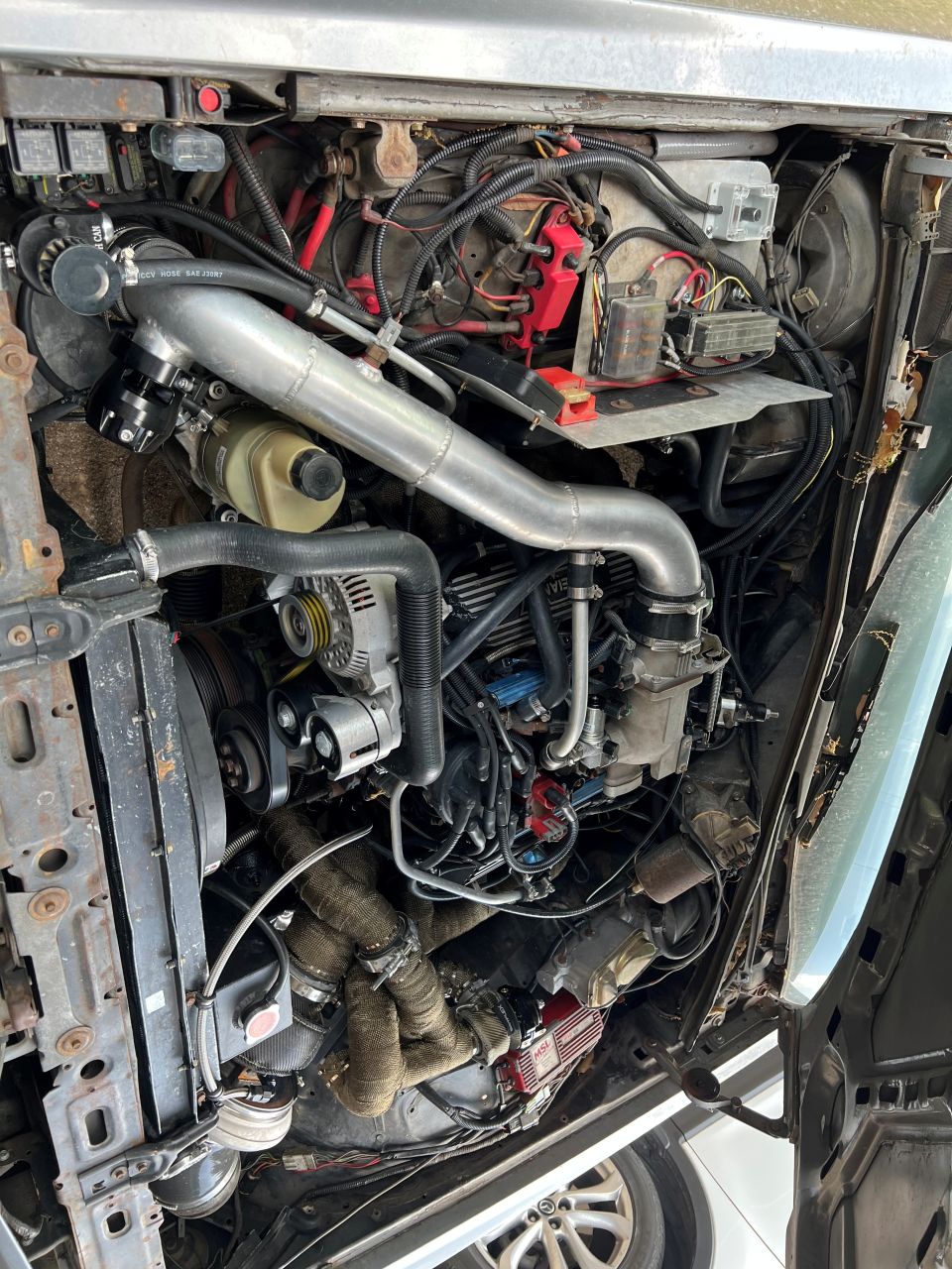 Overhead view of a modified V8 engine bay with turbocharger and custom piping.