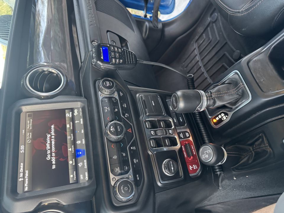Interior of a 2022 Jeep Wrangler showing the center console, CB radio, infotainment screen, and gear shifter.