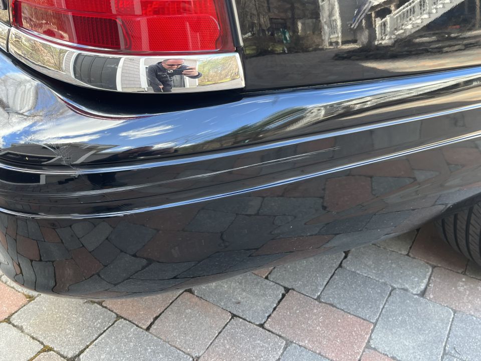 Close-up of a black Ford Crown Victoria rear bumper, taillight and chrome trim