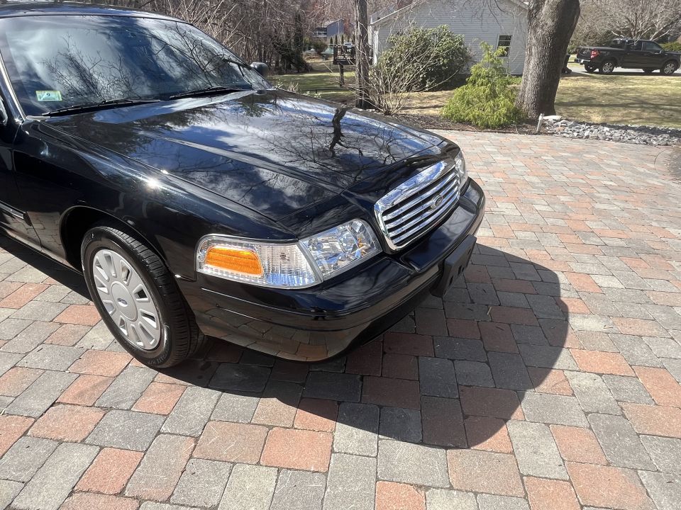 Driver-side front corner and headlight of a black Ford Crown Victoria