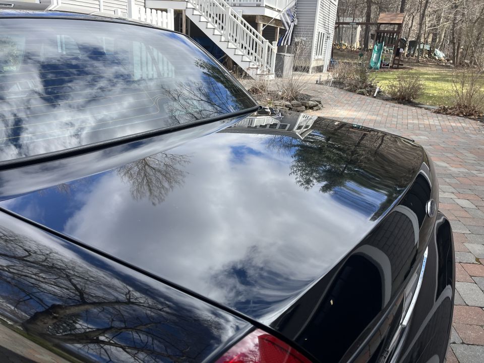 Rear deck and trunk lid of a black Ford Crown Victoria with sky reflection