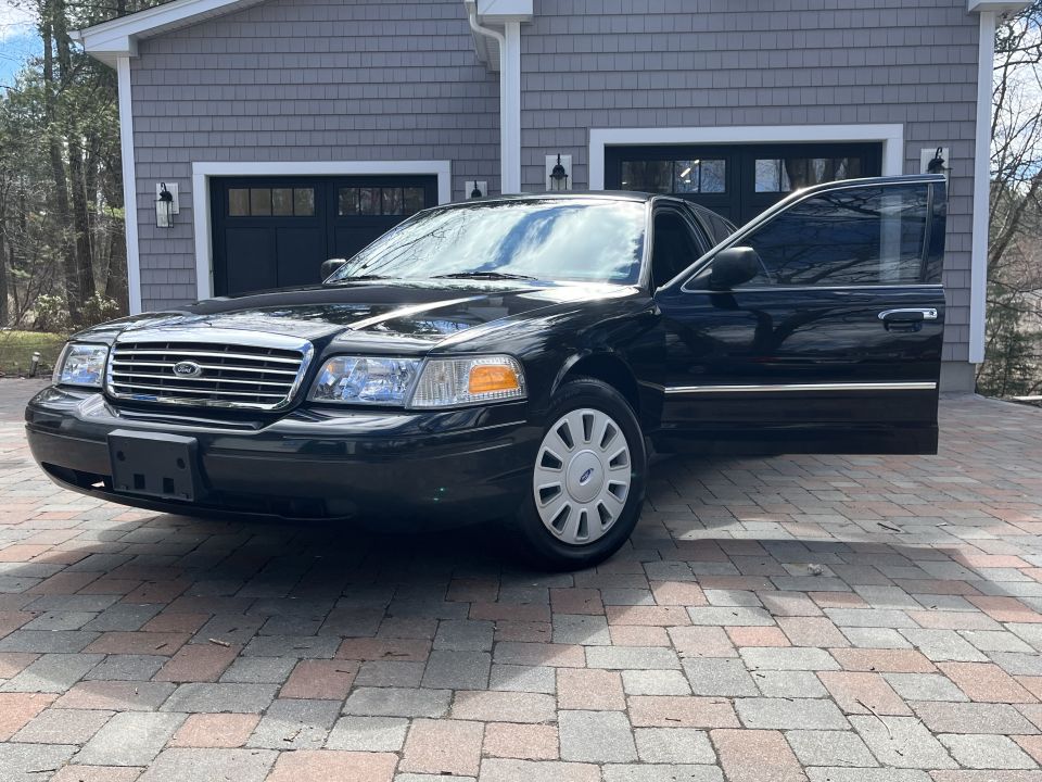 Black Ford Crown Victoria parked on a paver driveway