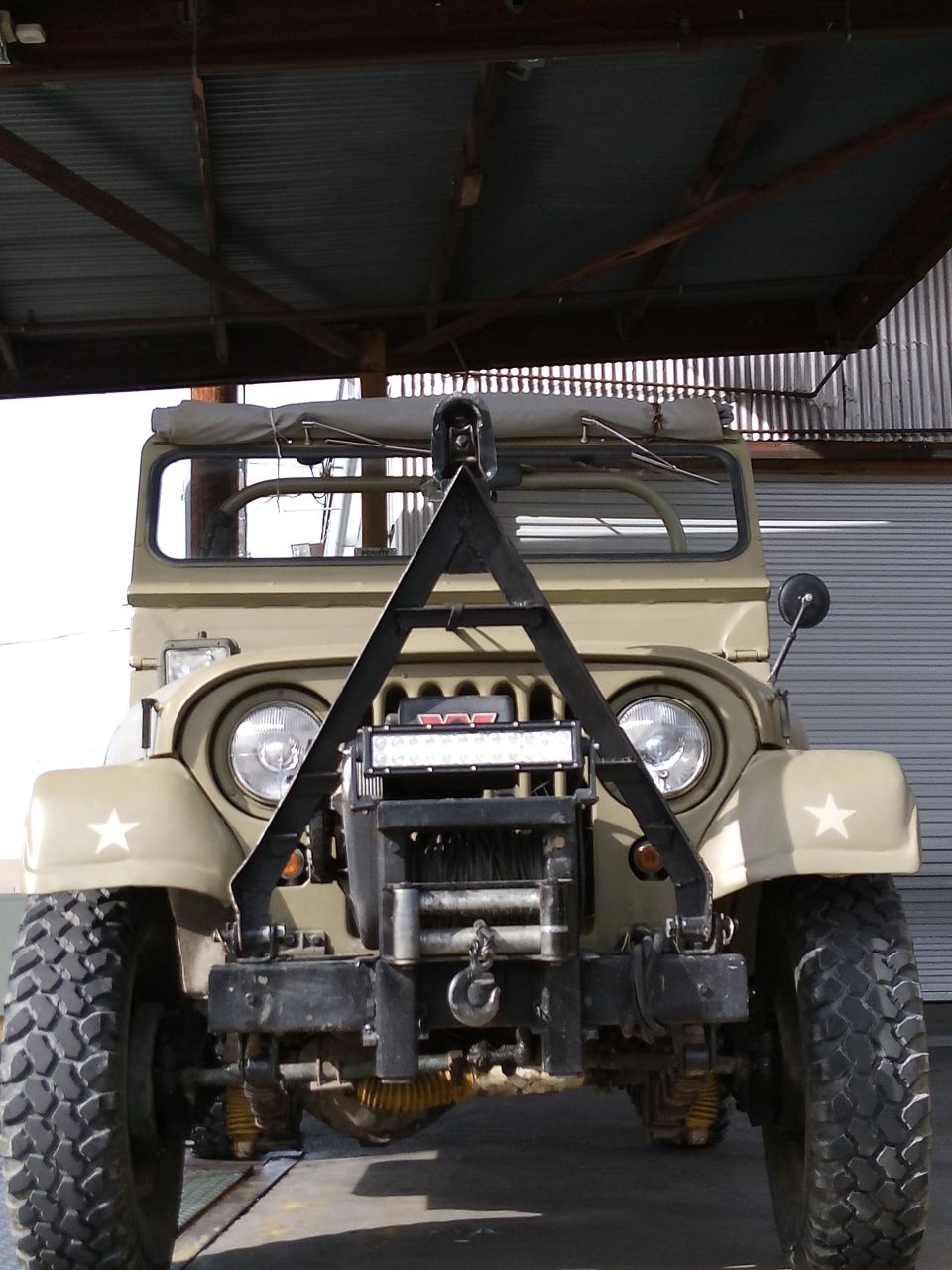 Tan Jeep CJ5 with winch and light bar, front view