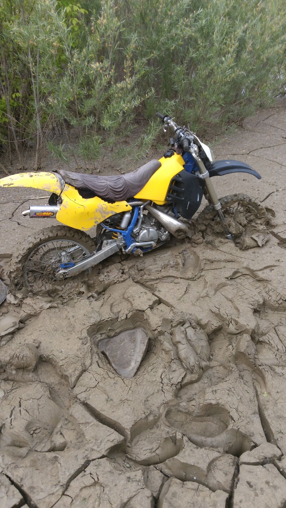 Yellow dirt bike stuck in mud.