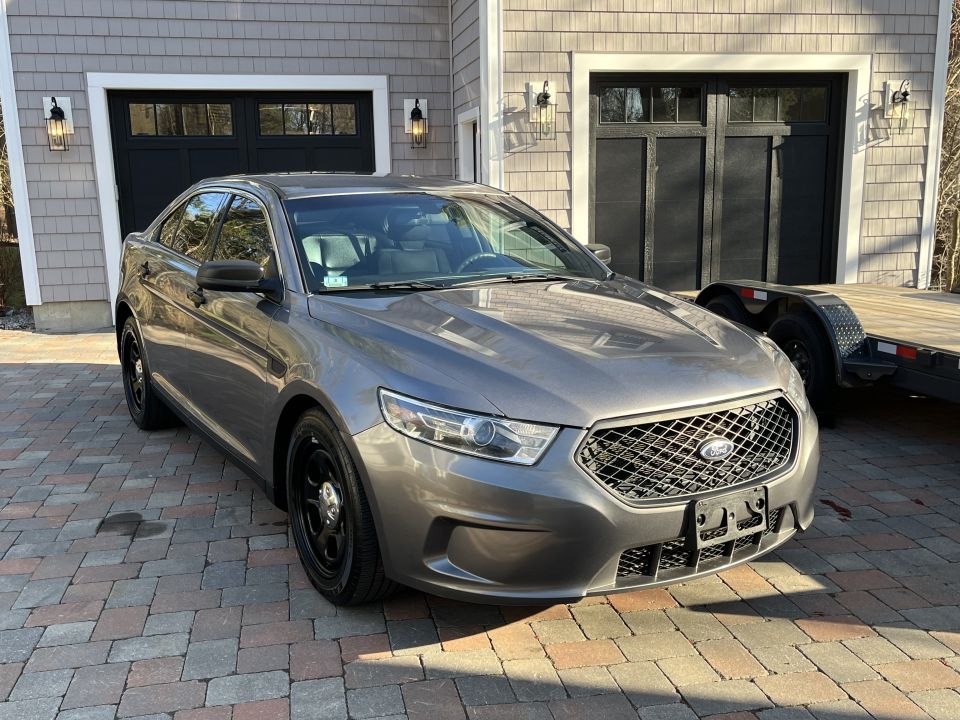 Gray Ford Taurus parked on a paver driveway
