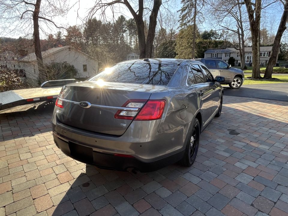 Gray Ford Taurus sedan rear three-quarter view in driveway