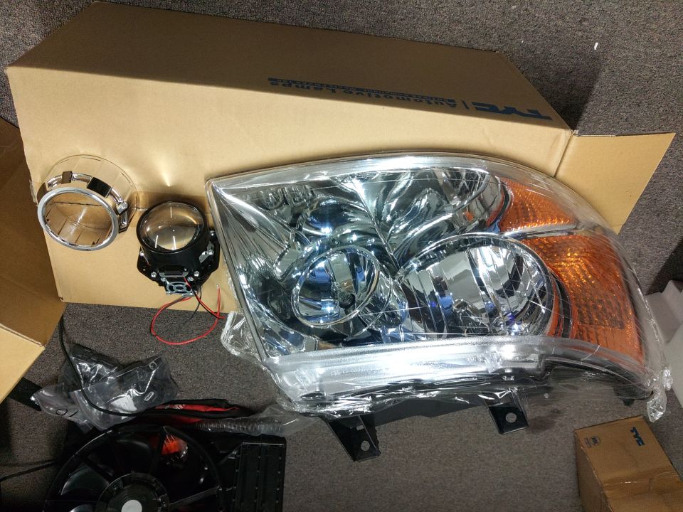 Aftermarket chrome headlight assembly with projector lens and retrofit parts on box