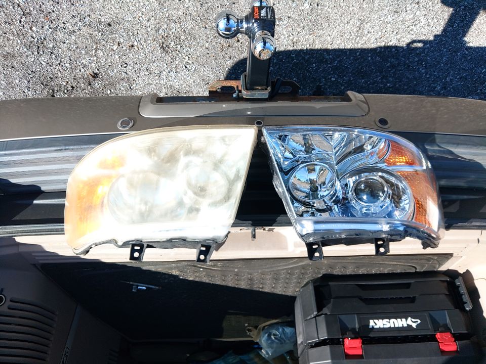 Old yellowed headlight next to a new clear headlight, with a Husky tool case below