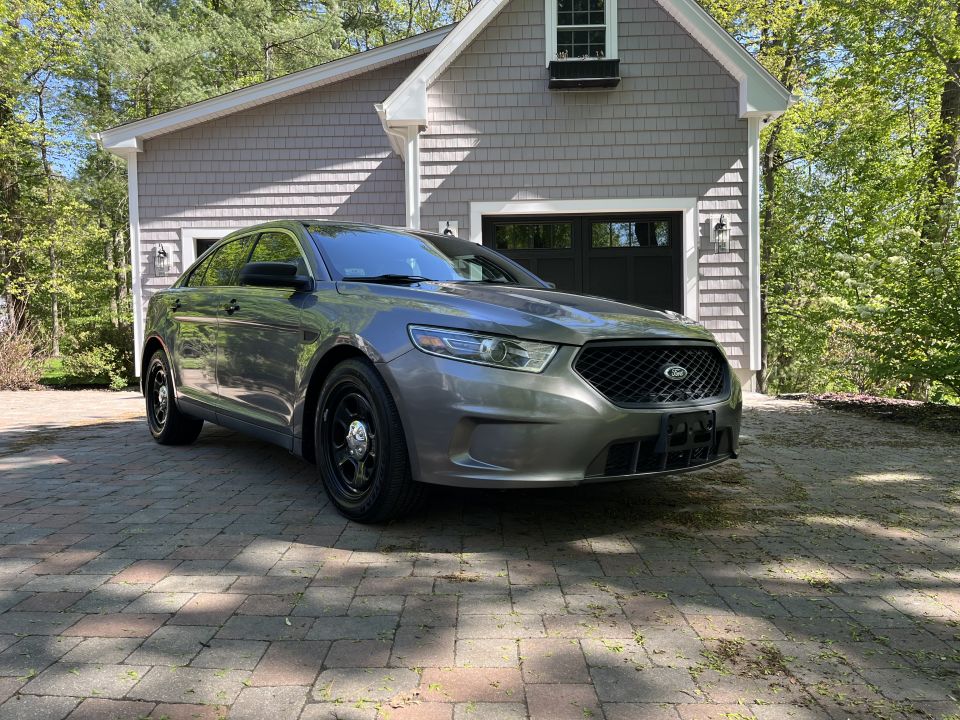 Gray sedan with black wheels parked on a brick driveway