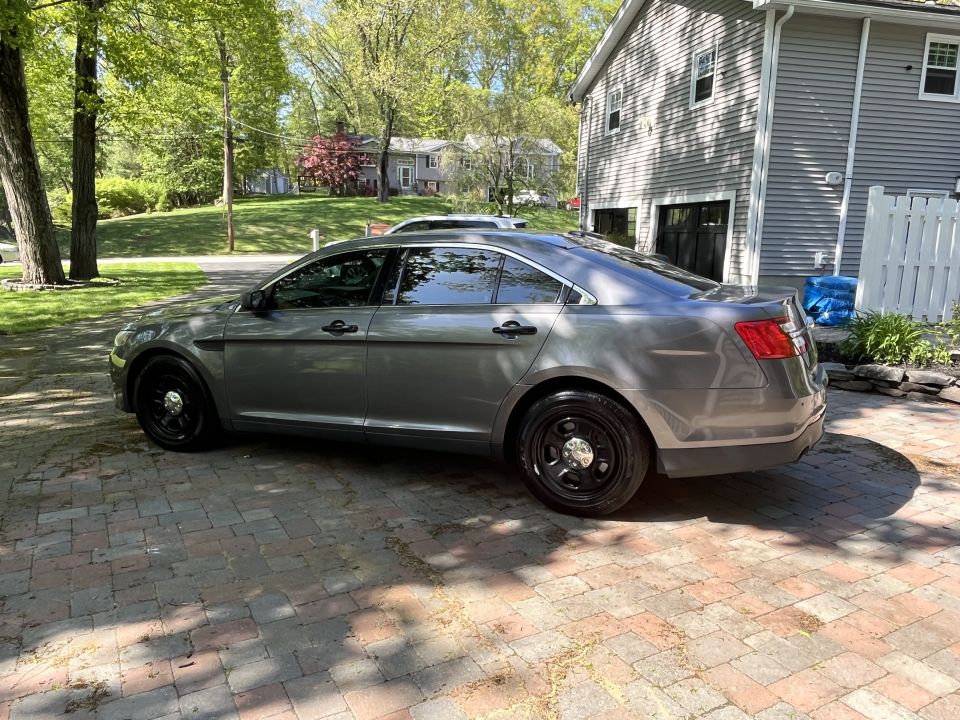 Gray sedan parked on a brick driveway, side view. Black steel wheels, tinted windows