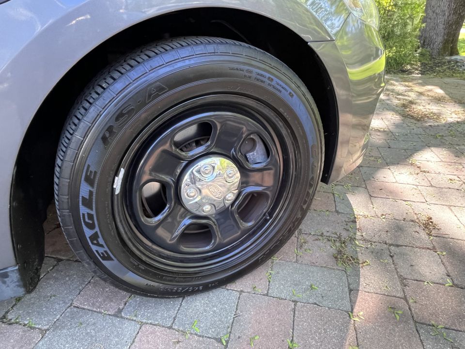 Gray car's black steel wheel with chrome center cap and Eagle tire