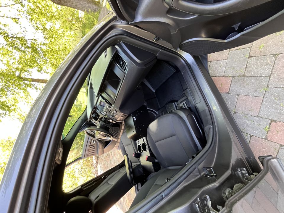 Interior view of a police car, showing front seats, dashboard, and center console with cup holders