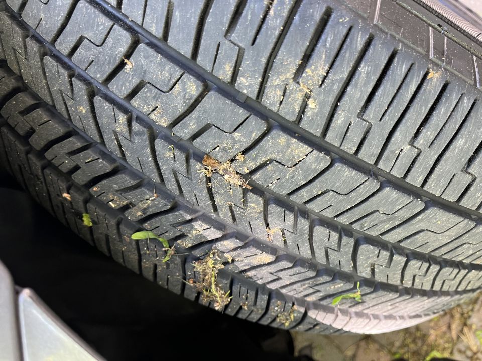 Close-up of a tire tread with dirt and grass stuck in it