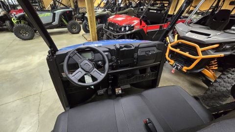2025 Polaris RANGER - The interior of a blue UTV is shown, with other utility vehicles visible in the showroom.