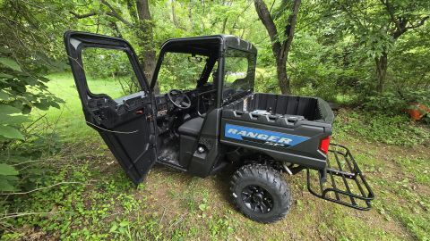 2025 Polaris RANGER - Black Polaris Ranger side-by-side with doors open, parked outdoors in a wooded area.