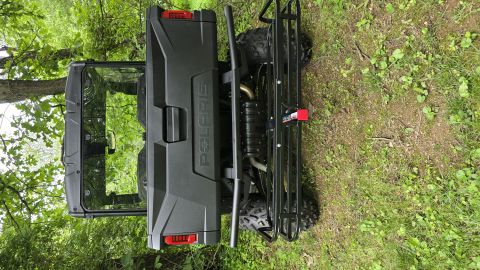 2025 Polaris RANGER - A black Polaris RANGER side-by-side is viewed from the rear, parked outdoors amongst trees and grass.