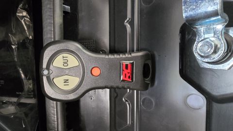 2025 Polaris RANGER - Close-up of a winch remote control unit with 'IN' and 'OUT' buttons.