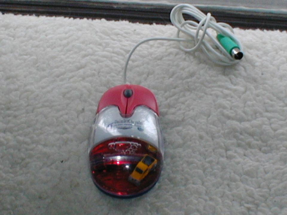 Red and silver computer mouse with a yellow toy car visible inside its transparent red base