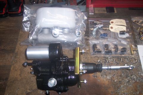 1978 Ford Bronco - A brake master cylinder and reservoir kit is laid out on a workbench with various fittings and clamps.