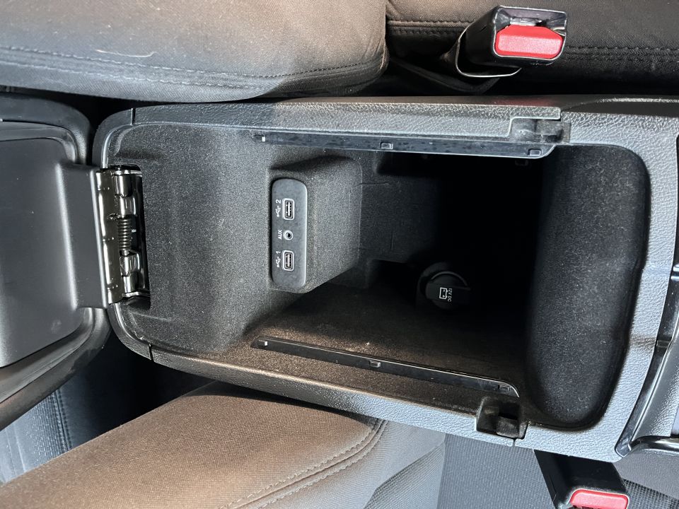 Open center console storage bin with USB ports and a 12V outlet