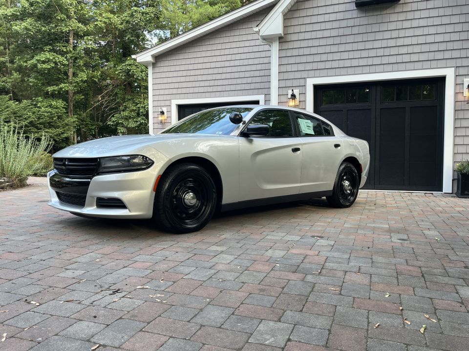 Front three-quarter exterior view of a silver Dodge Charger on pavers