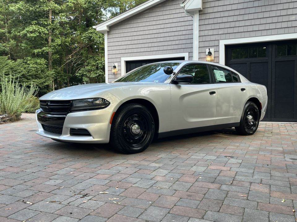 Silver sedan with black steel wheels parked on a brick driveway in front of a garage