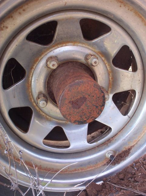 1988 Ford Bronco - A close-up view of a rusted wheel hub and lug nuts on a vehicle part.
