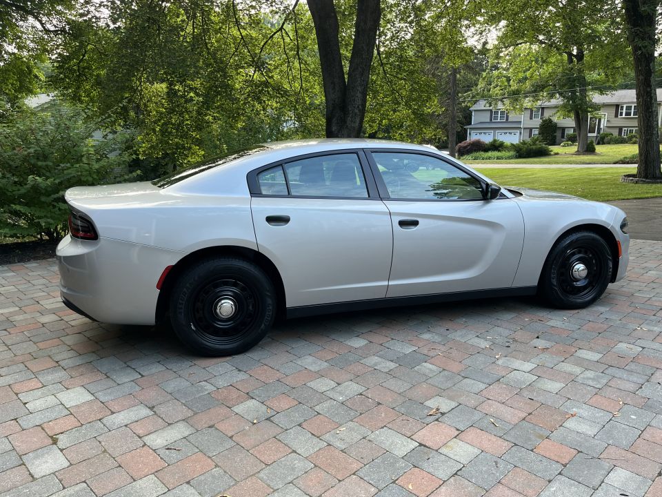 Silver Dodge Charger sedan passenger-side profile on brick pavers