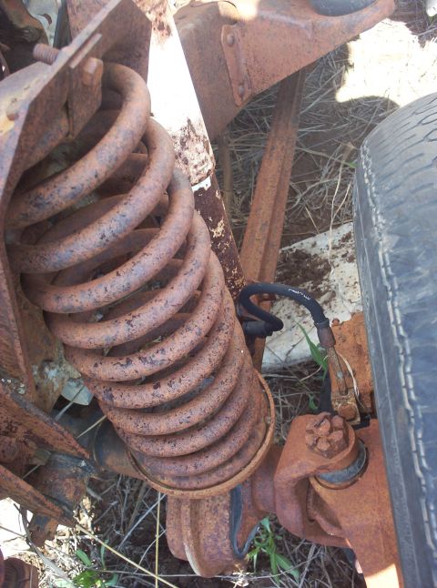 1988 Ford Bronco - Close-up of heavily rusted vehicle suspension components, including a coil spring and part of a tire.