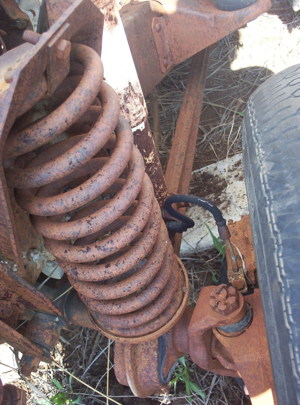 Rusty coil spring and suspension parts with a tire visible on the right