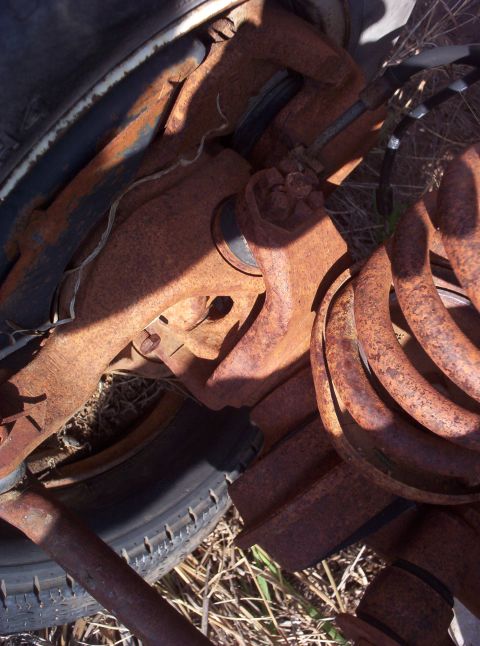 1988 Ford Bronco - Heavily rusted vehicle suspension parts are shown in detail, with a tire visible in the background.