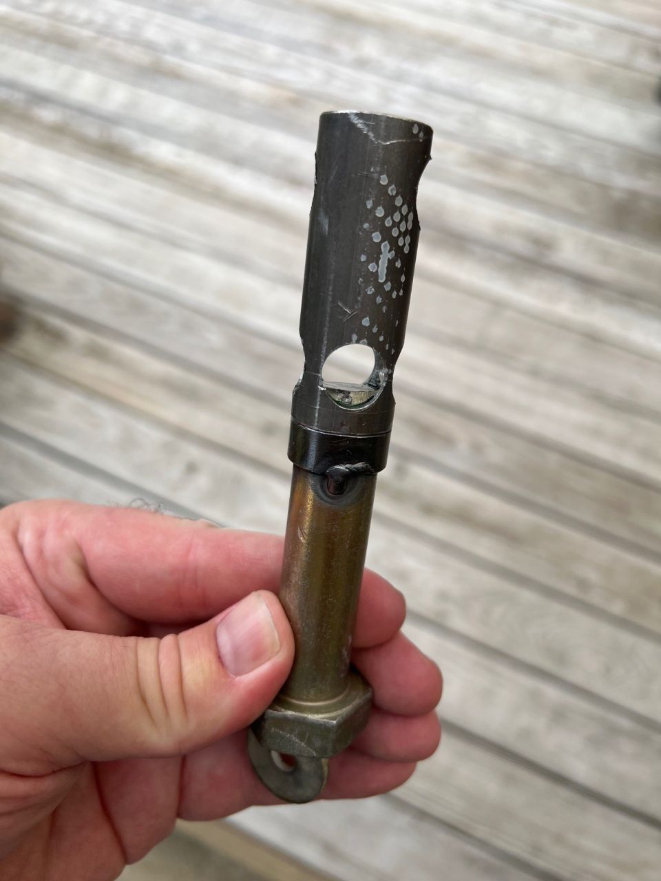 Metal part with hex nut and washer, and damaged cylindrical top with cutout.