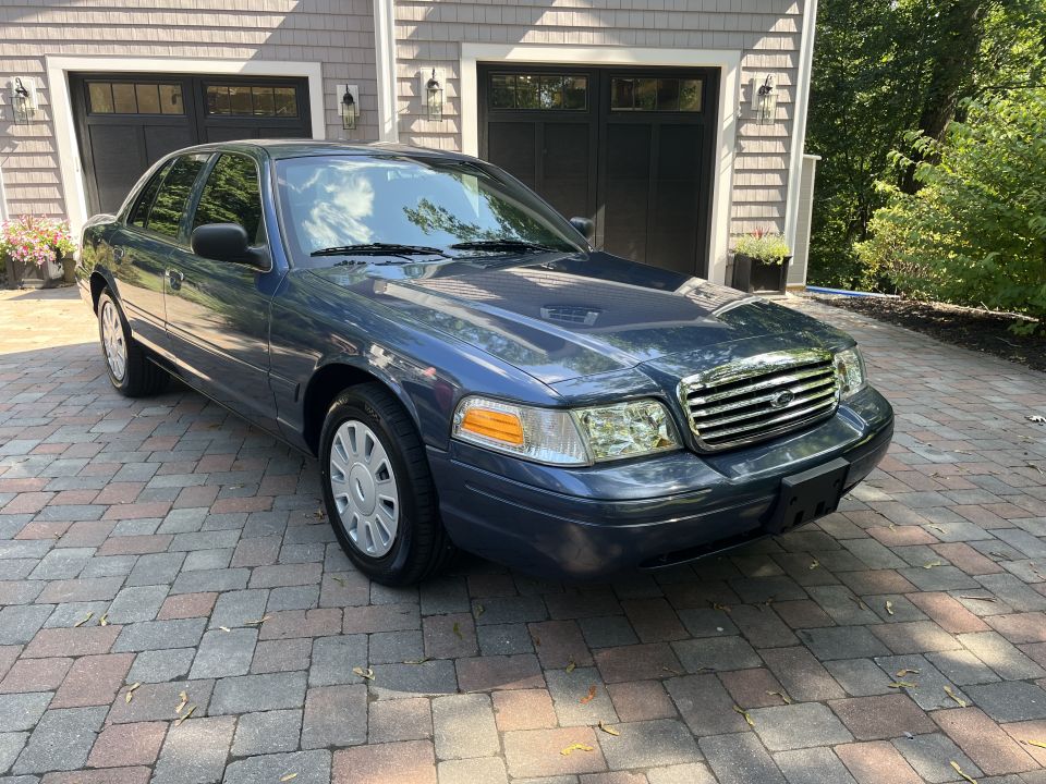 Blue Ford Crown Victoria front three-quarter view near garage doors