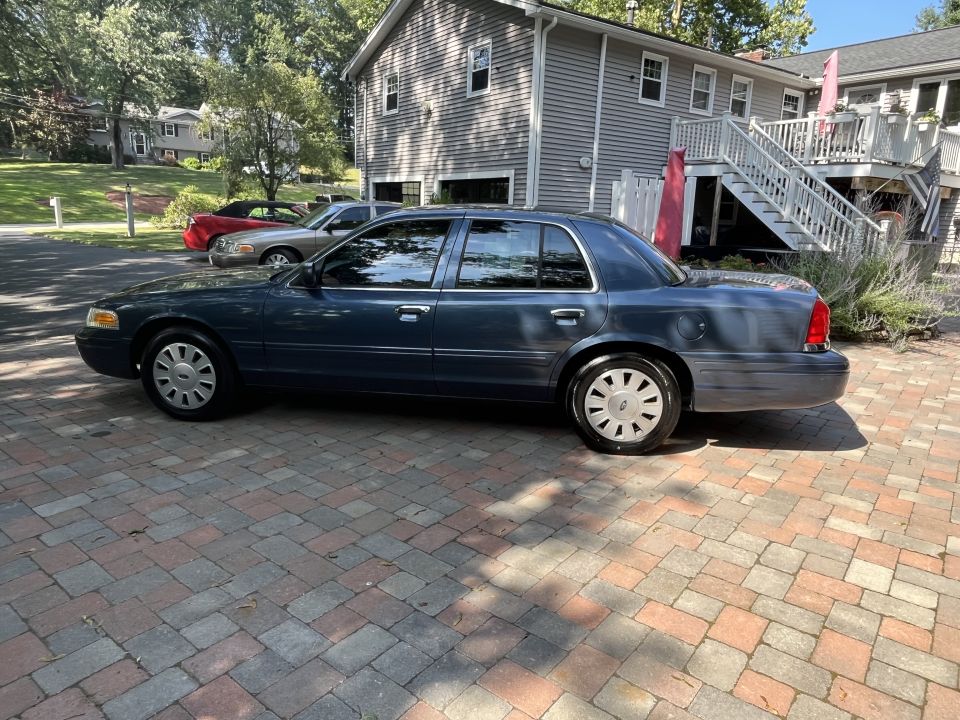 Blue Ford Crown Victoria driver-side profile in driveway