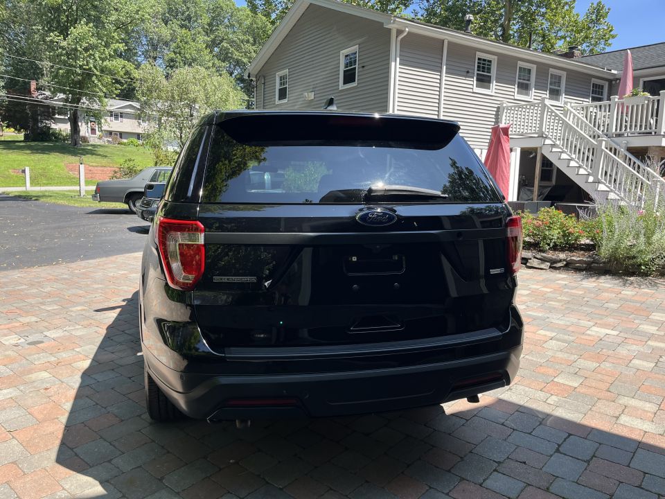 Black Ford Explorer SUV rear view on paver driveway