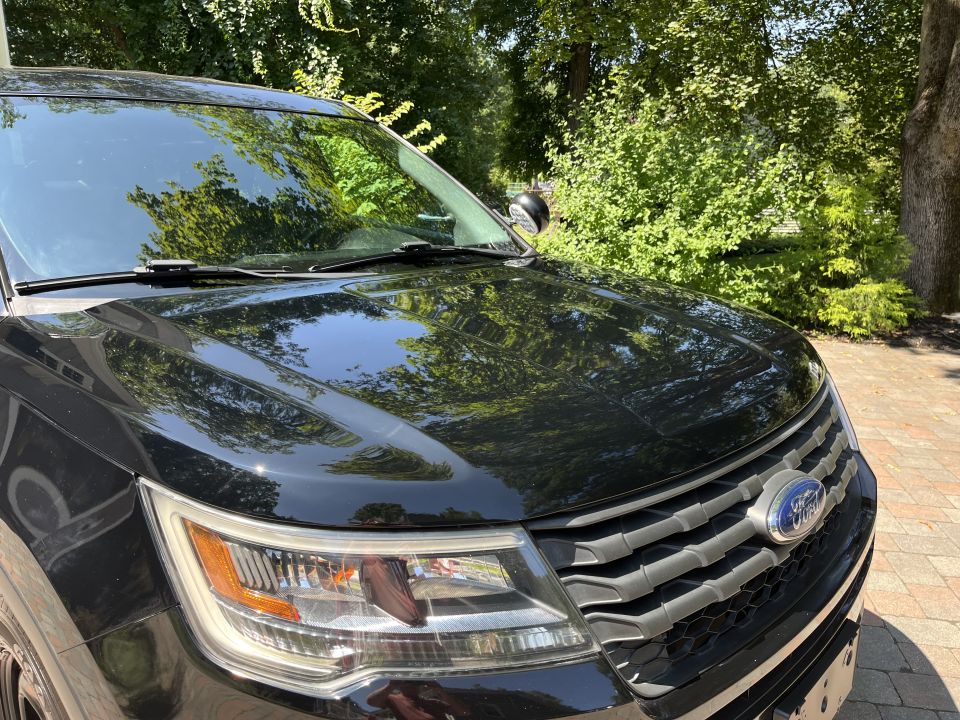 Close-up of black Ford Explorer hood, headlight and grille