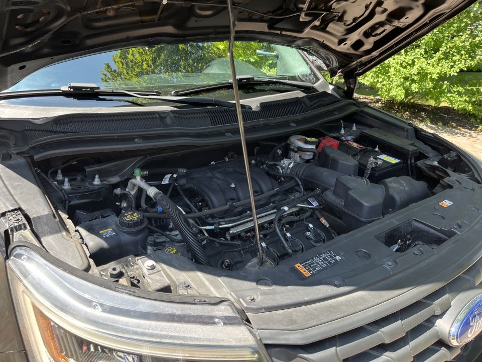 Open engine bay of Ford Explorer showing engine, battery and intake
