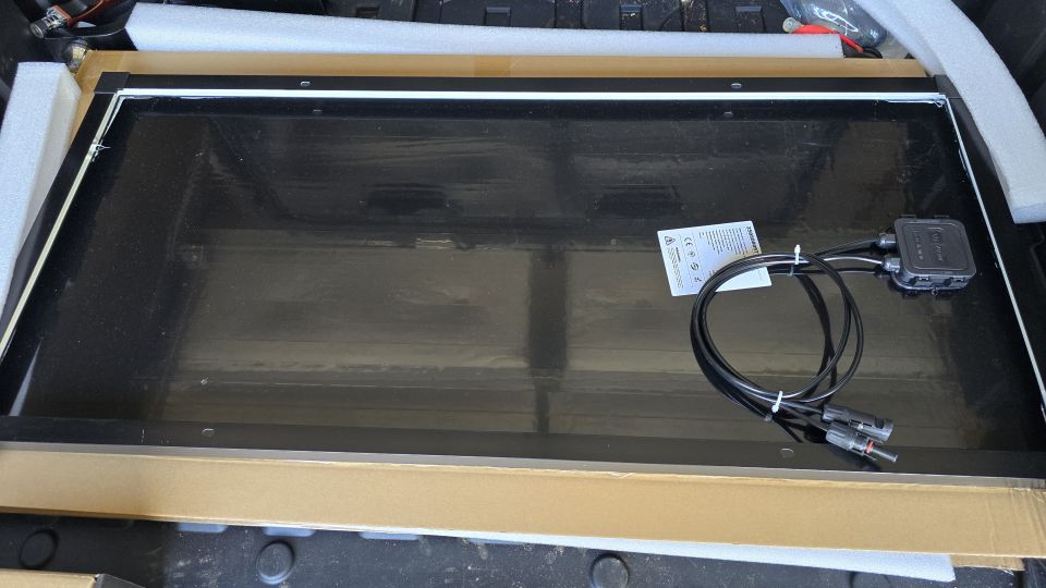Solar panel with cables and junction box, sitting in packaging