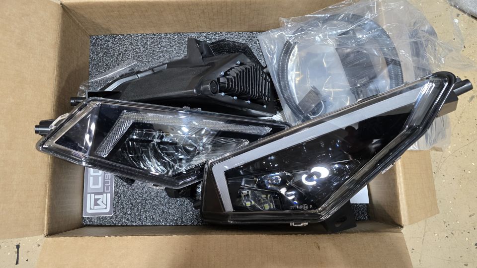 Boxed pair of new LED headlight assemblies with wiring and black trim parts for a Polaris Ranger