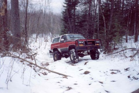 1995 Ford Bronco - A lifted GMC Jimmy navigates a snowy, wooded trail.