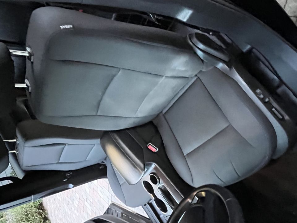 Car interior with gray cloth seats and a center console with cup holders. Airbag label visible on seat