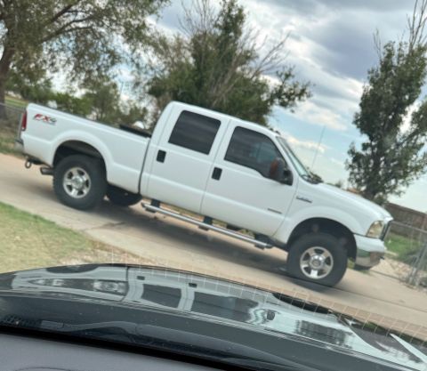 2005 Ford F-250 - A white 2005 Ford F-250 Super Duty pickup truck is viewed from a three-quarter front angle, showing its crew cab and FX4 badging.