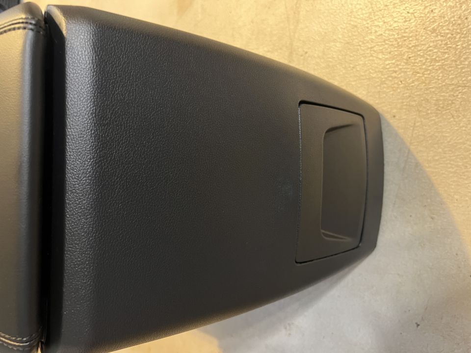 Black leather center console armrest lid with a small storage compartment